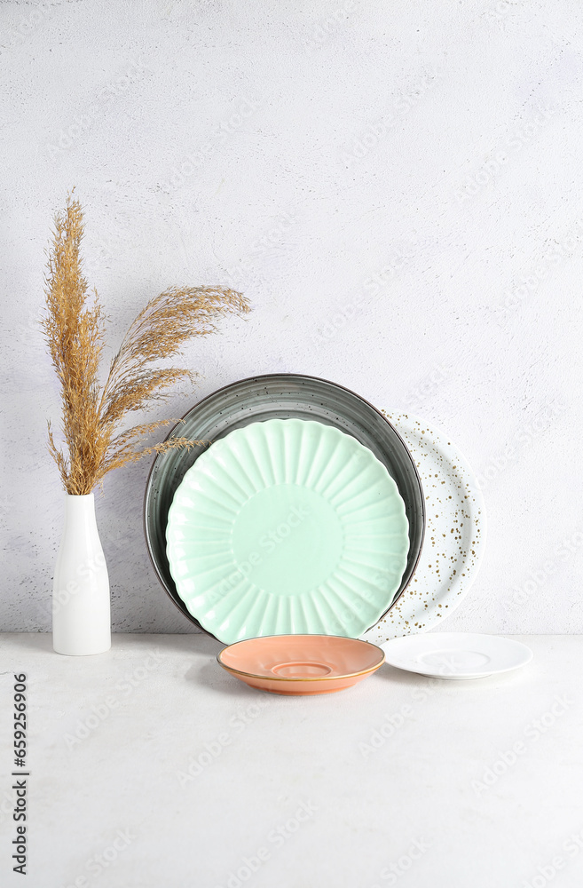 Clean plates and vase with pampas grass on white table