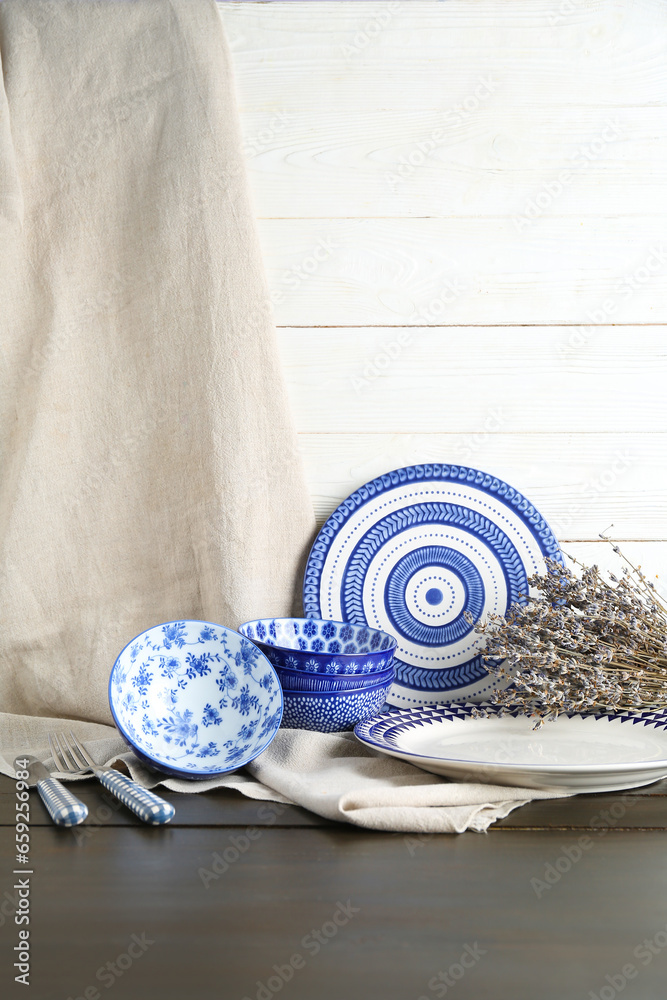 Set of clean blue dishes and dried lavender on black wooden table