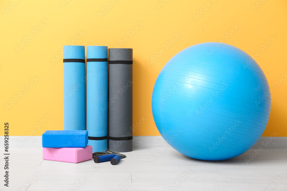 Fitness ball, yoga mats, blocks and skipping rope on floor in gym