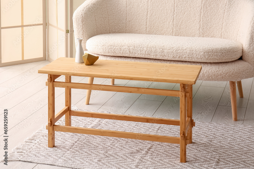 Wooden coffee table with vase and decor in interior of living room