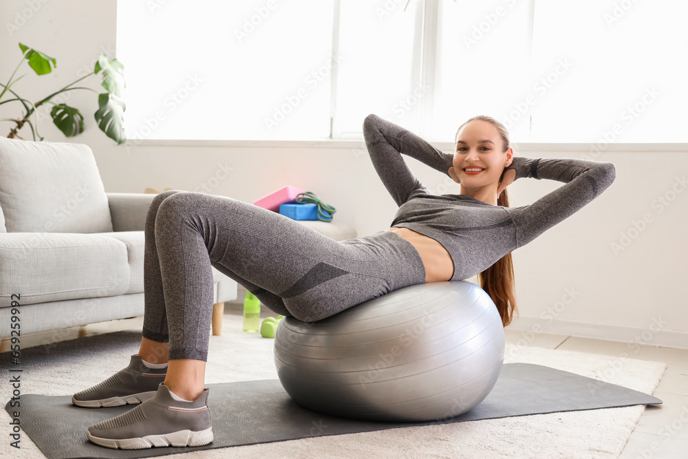 Sporty young woman training with fitball at home