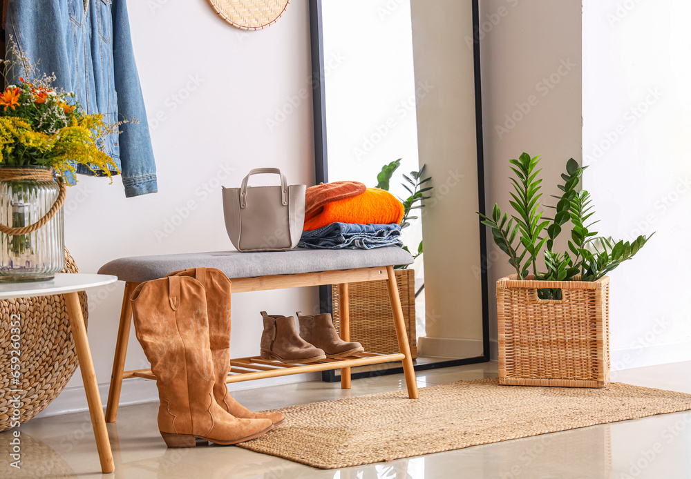 Interior of modern hallway with autumn clothes, mirror and bench