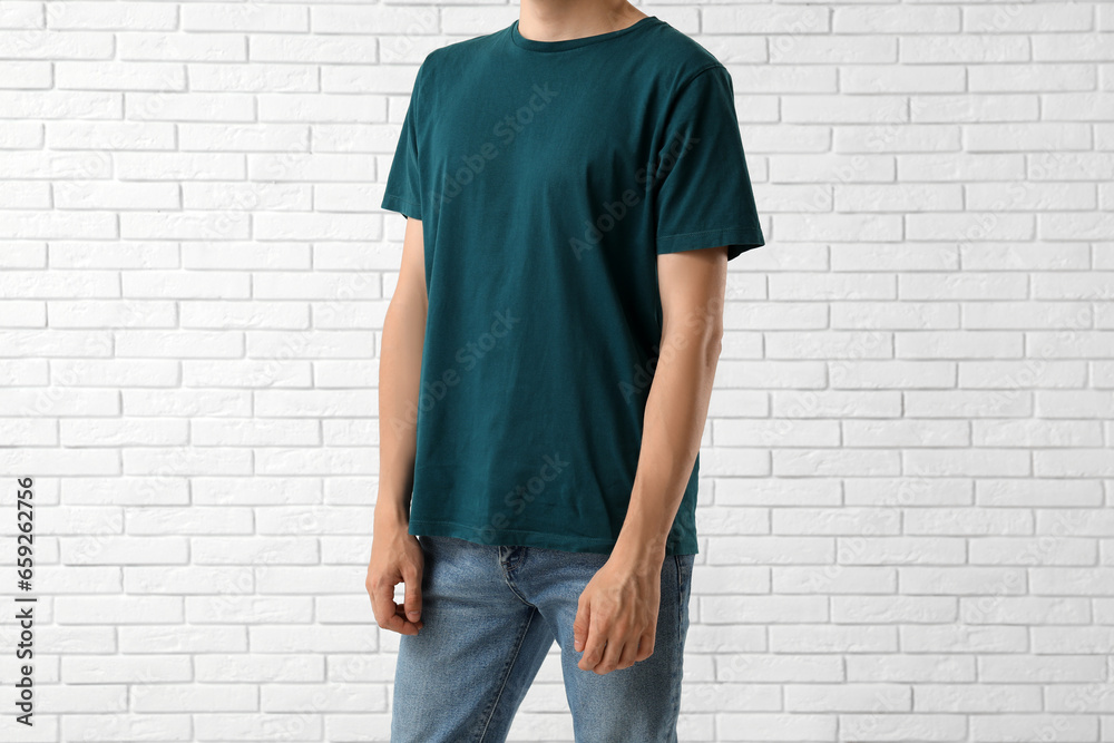 Man in stylish t-shirt near white brick wall