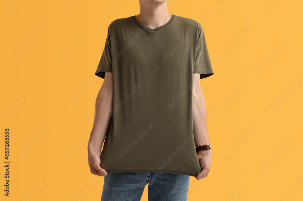 Handsome young man in stylish t-shirt on orange background