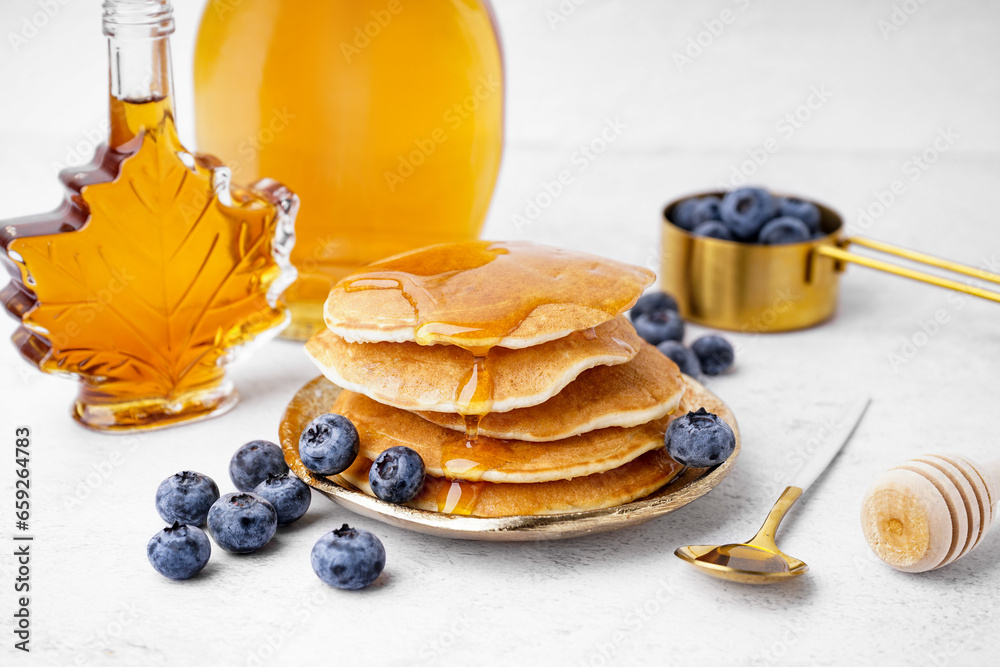 Plate of tasty pancakes with blueberries and maple syrup on white background