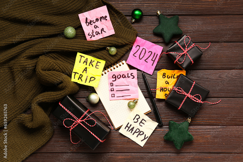 Sticky notes with different goals for 2024, Christmas balls, gift boxes and sweater on brown wooden background