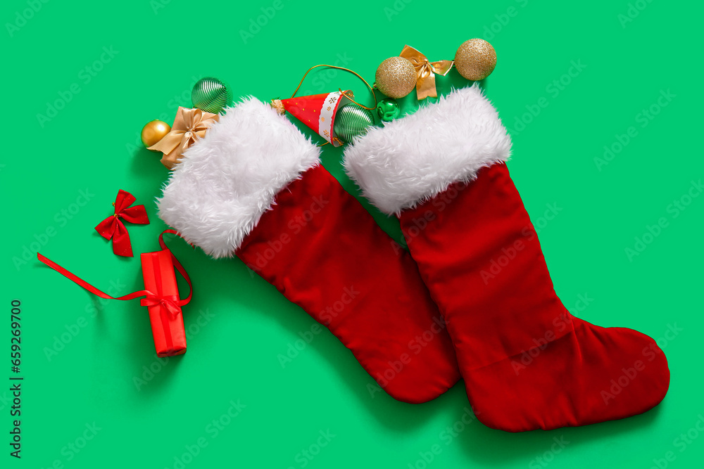 Christmas socks with balls and gift boxes on green background