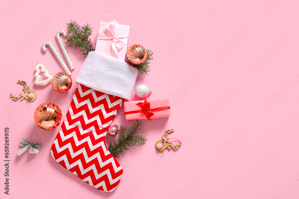 Christmas sock with tree branches, beautiful decorations and gift boxes on pink background