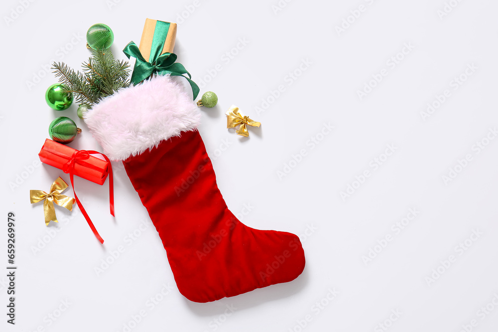 Christmas sock with tree branches, balls and gift boxes on white background