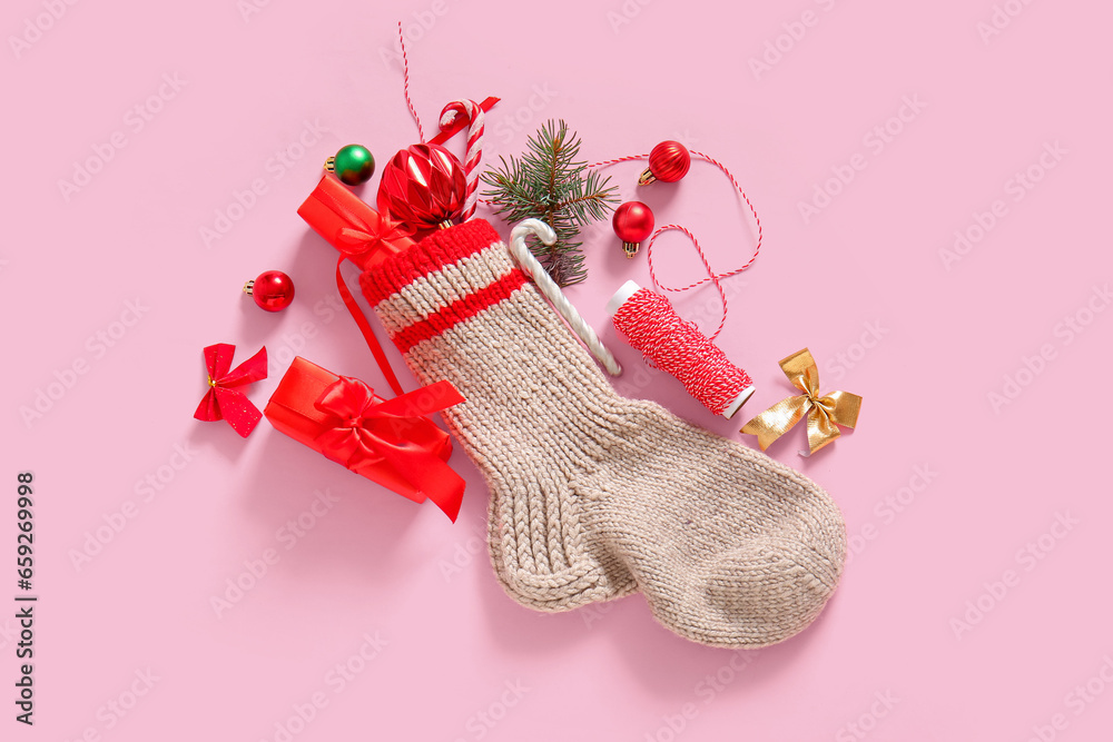 Christmas sock with beautiful decorations and gift boxes on pink background