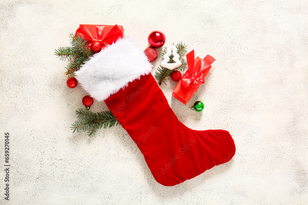 Christmas sock with tree branches, balls and gift boxes on white background