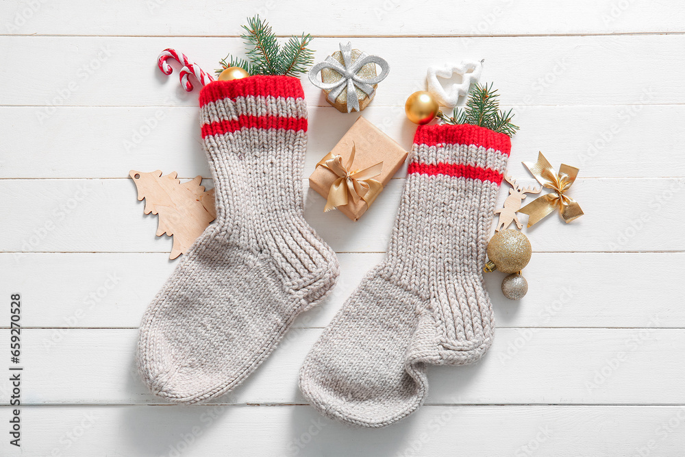 Christmas socks with beautiful decorations and gift boxes on white wooden background