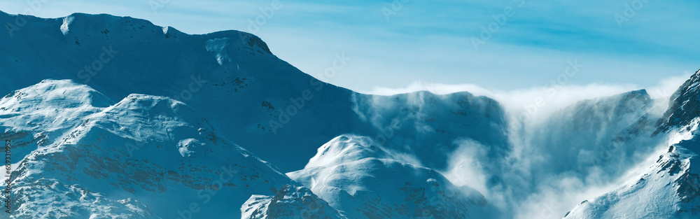 Clouds rolling over snowcapped mountain top in Julian Alps range during winter