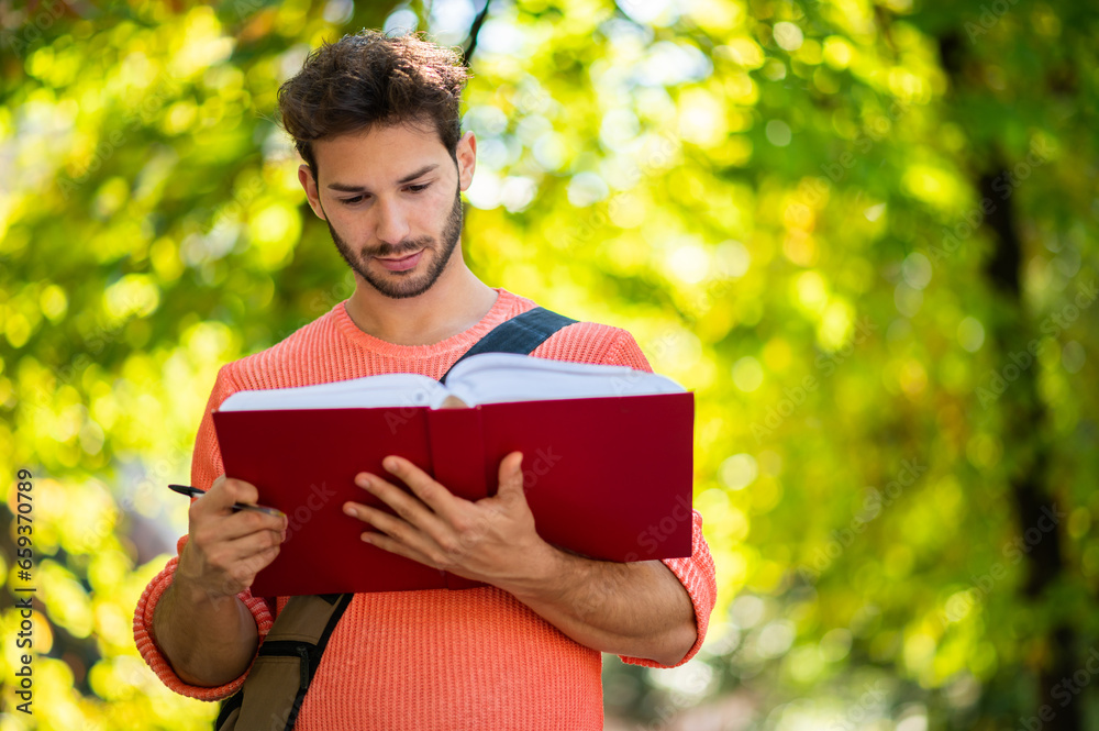 Young male student reading a book outdoor