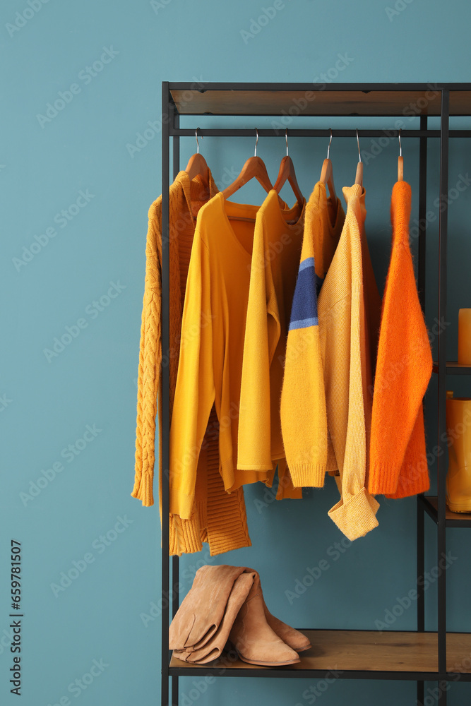 Shelving unit with clothes and shoes near blue wall