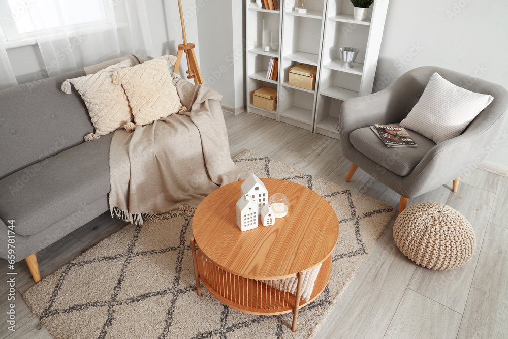 Interior of stylish living room with coffee table, grey armchair and cozy sofa