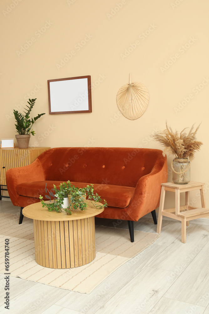 Interior of living room with cozy brown sofa, coffee table and wooden cabinet