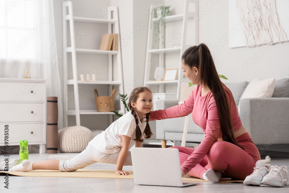 Working mother with her little daughter training at home