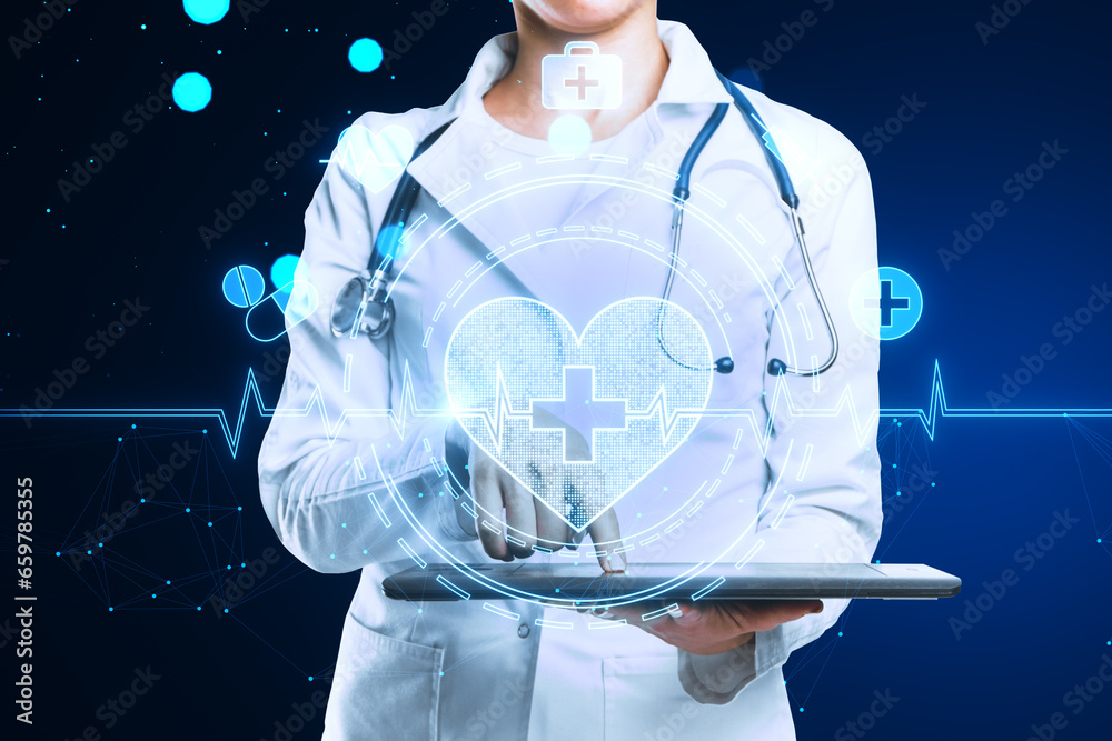 Close up of female doctor hands using tablet with glowing bright medical heart interface on blurry blue background. Innovation and cardiology concept.