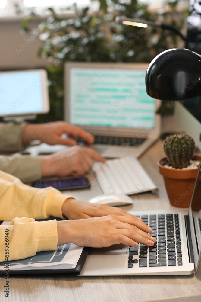 Female programmer working with laptop at table in office, closeup