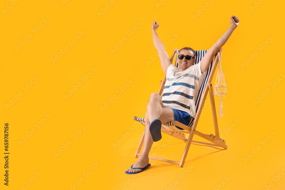 Mature man relaxing in deck chair on yellow background