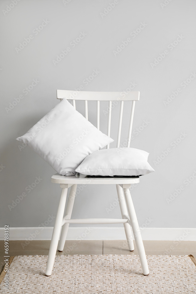 Chair with pillows on rug near white wall