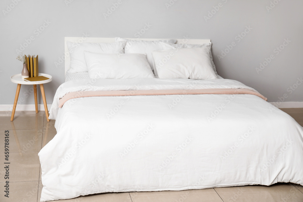 Interior of light bedroom with large double bed and white pillows