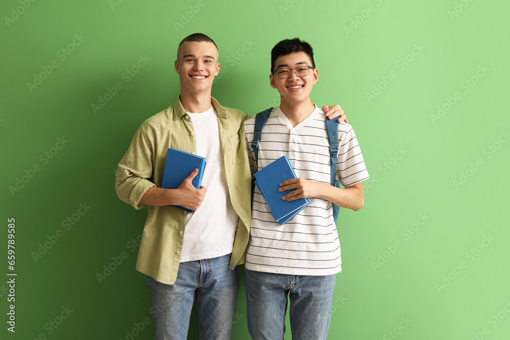 Happy male students with books on green background