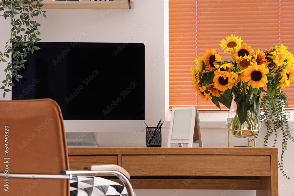 Vase with sunflowers on table in modern office