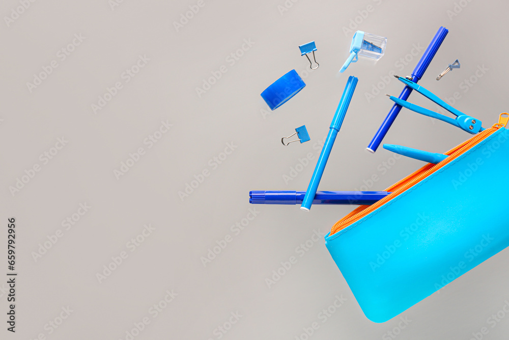 Flying blue pencil case and school stationery on grey background