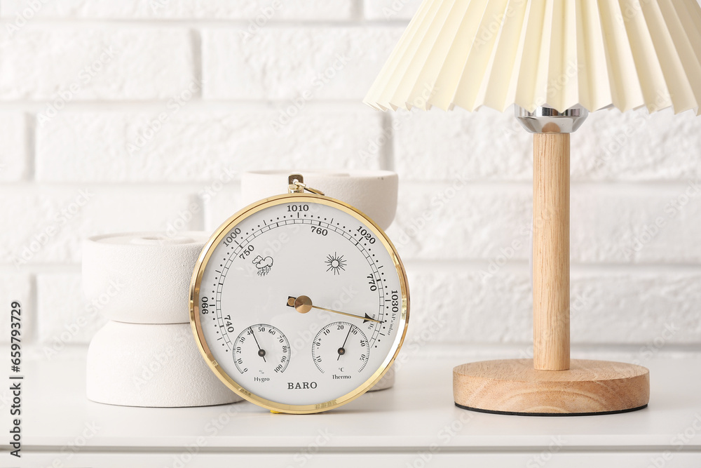 Aneroid barometer and lamp on table in room, closeup