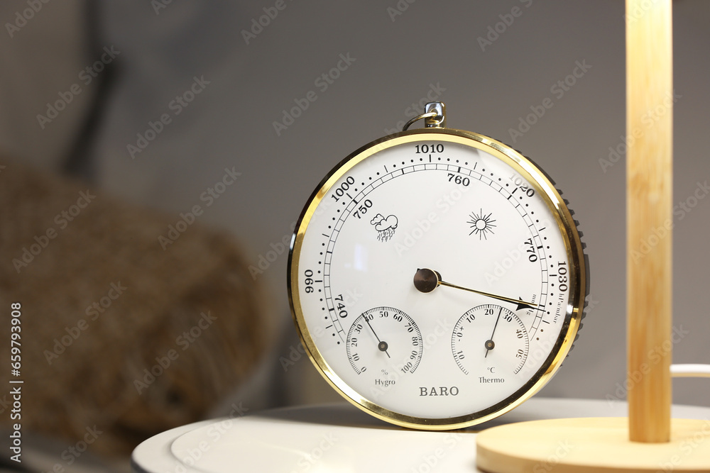 Aneroid barometer and glowing lamp on bedside table, closeup