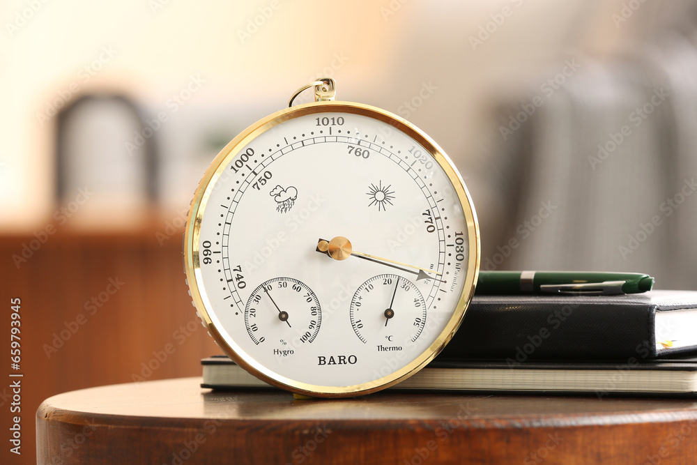 Aneroid barometer and books on table in room, closeup