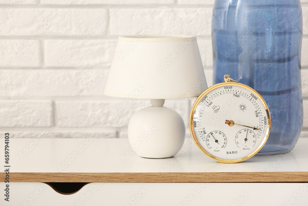 Aneroid barometer and lamp on table in room, closeup