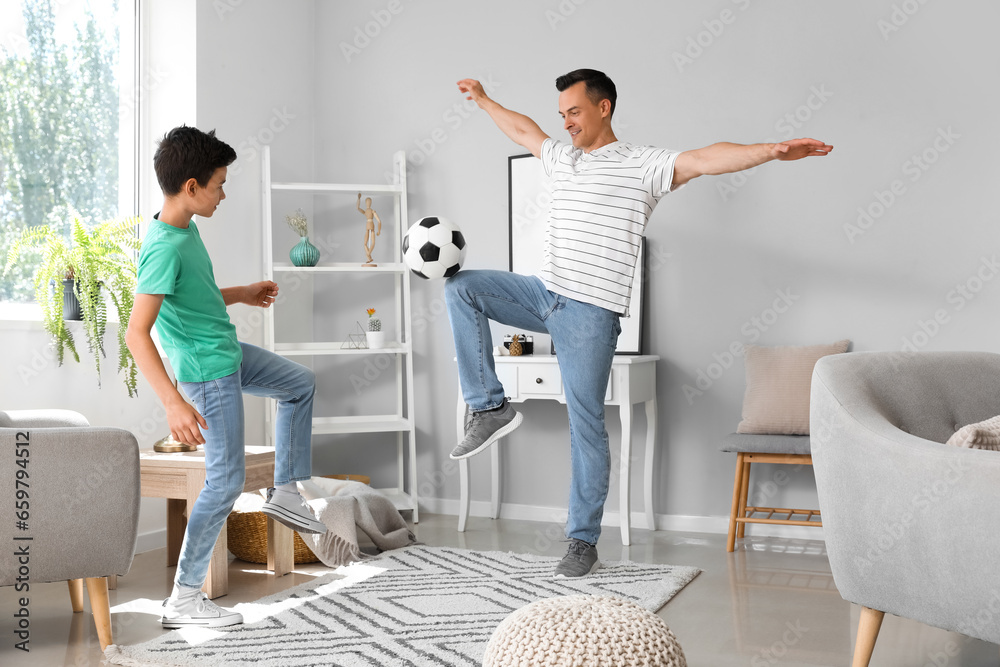 Little boy with his dad playing football at home