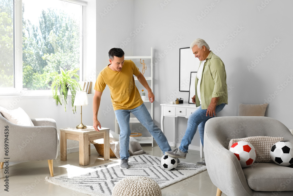 Young man with his father playing football at home