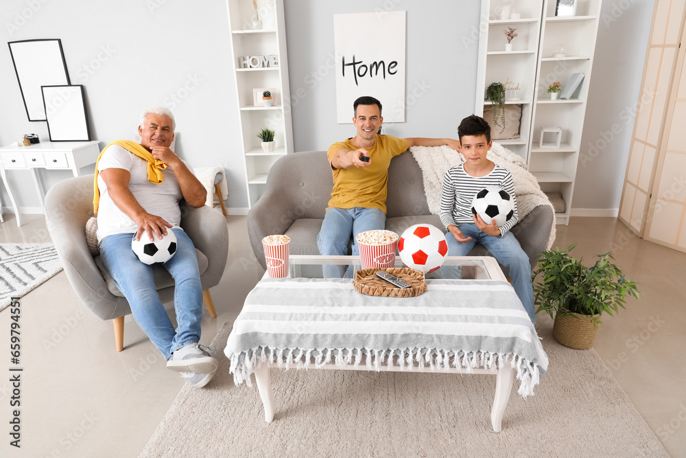 Little boy with his dad and grandfather watching football game at home