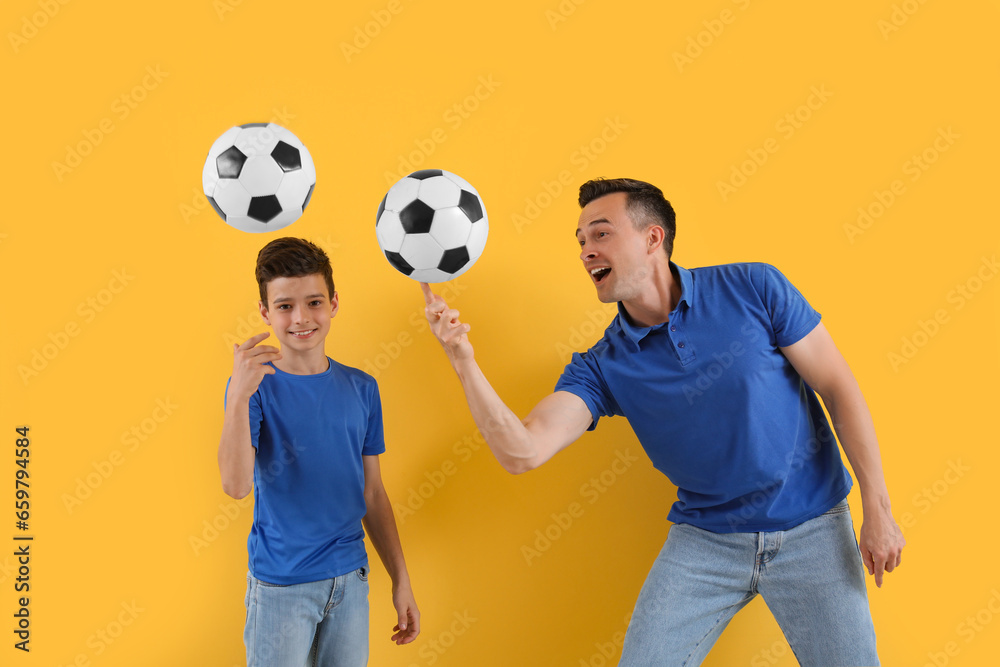 Little boy with his dad playing football on yellow background