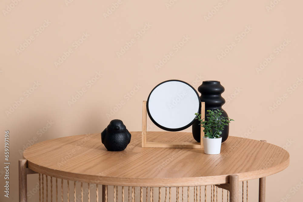 Wooden coffee table with mirror and decor near beige wall