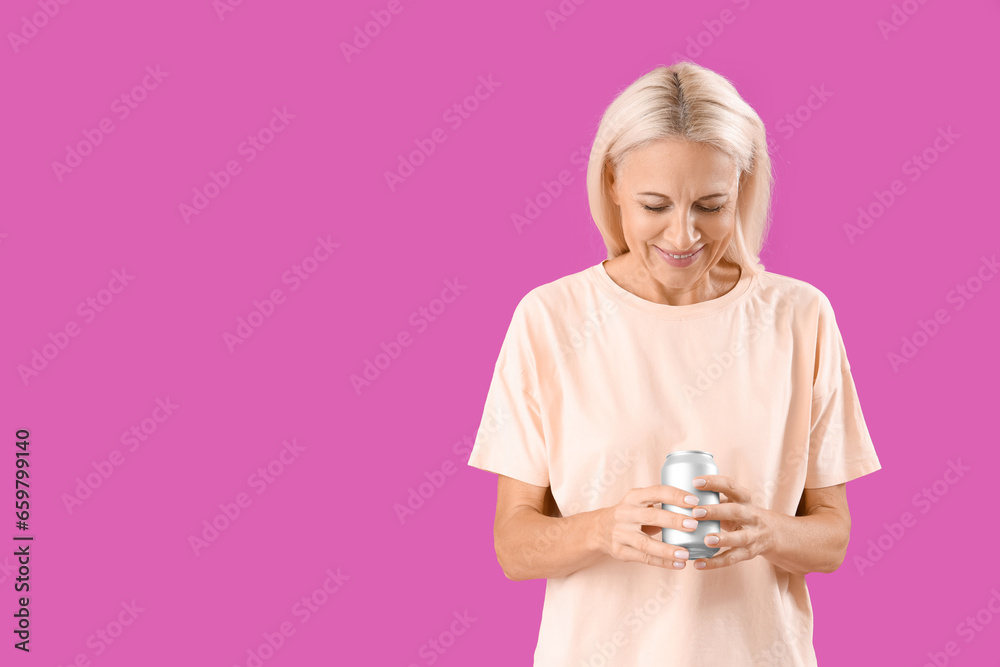 Mature woman with can of soda on purple background