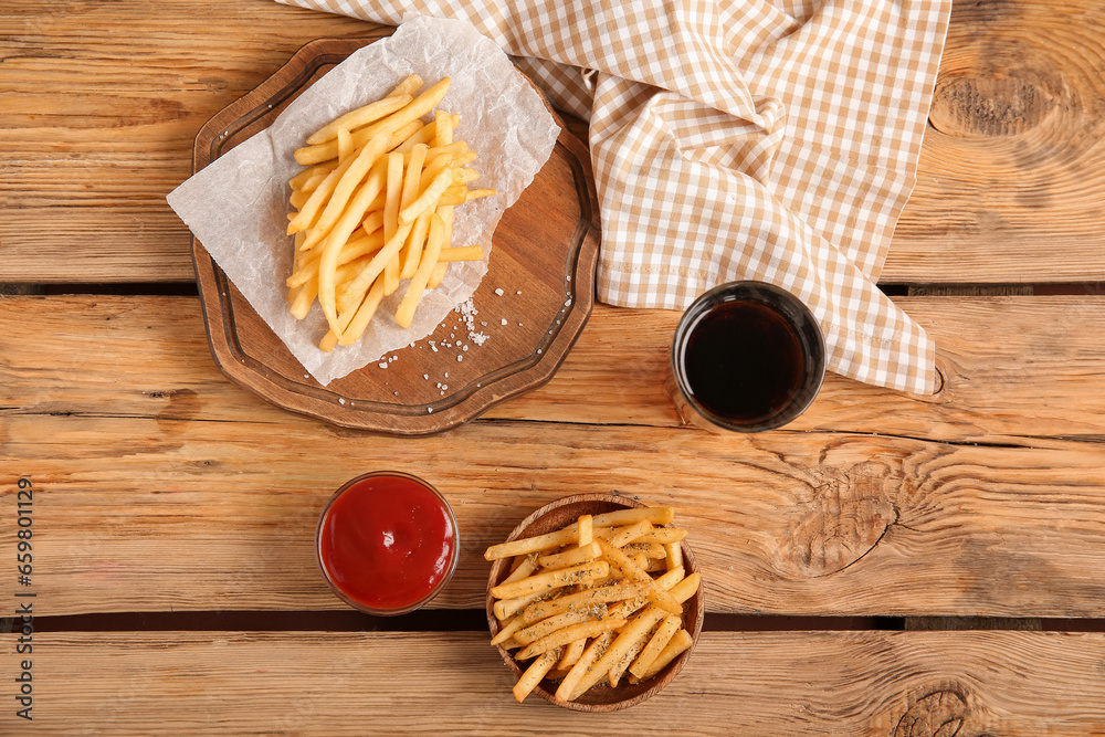 Bowl with tasty french fries, cola and bowl of ketchup on brown wooden background