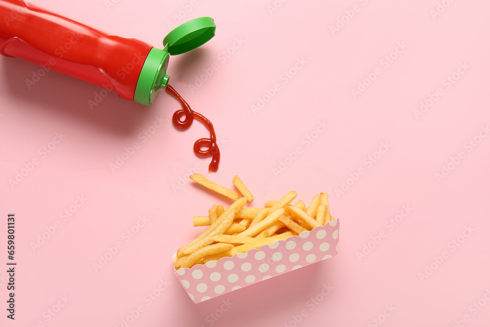 Paper box with tasty french fries and bottle of ketchup on pink background