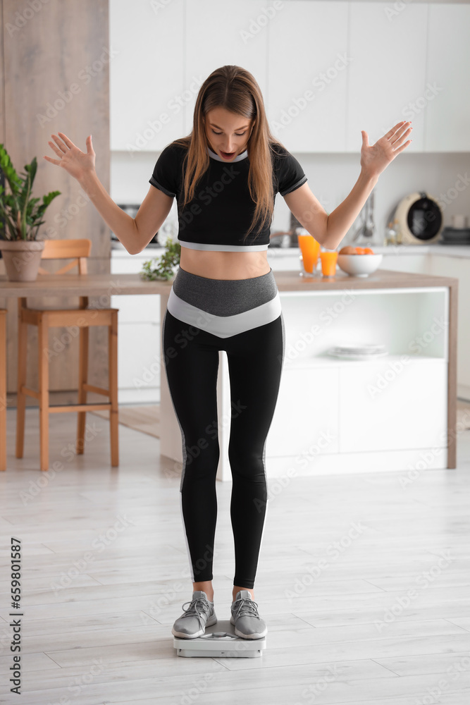 Shocked beautiful young woman with scales in kitchen. Weight loss concept