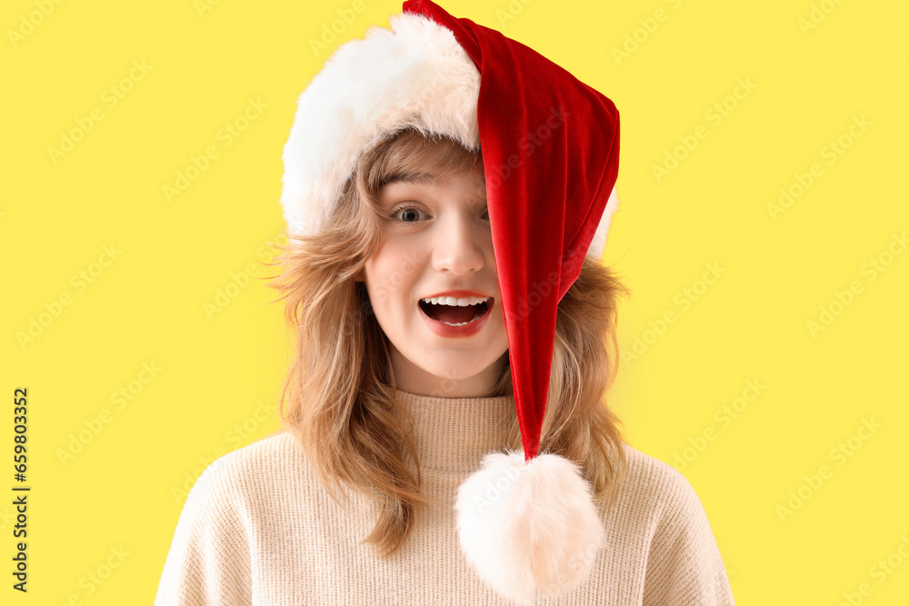 Young woman in Santa hat on yellow background, closeup