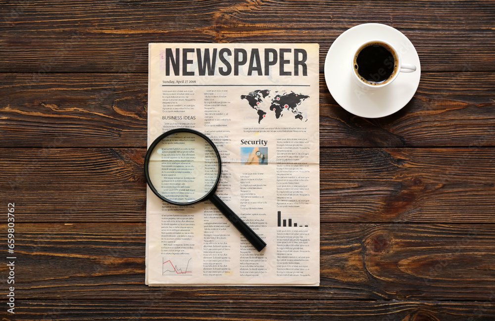 Morning newspaper, magnifying glass and cup of coffee on wooden background