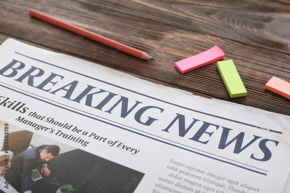 Morning newspaper, pencil and bookmarks on wooden background