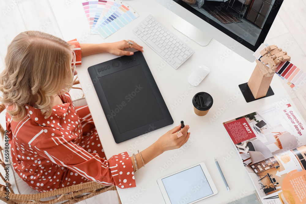 Female interior designer working with graphic tablet at table in office, top view