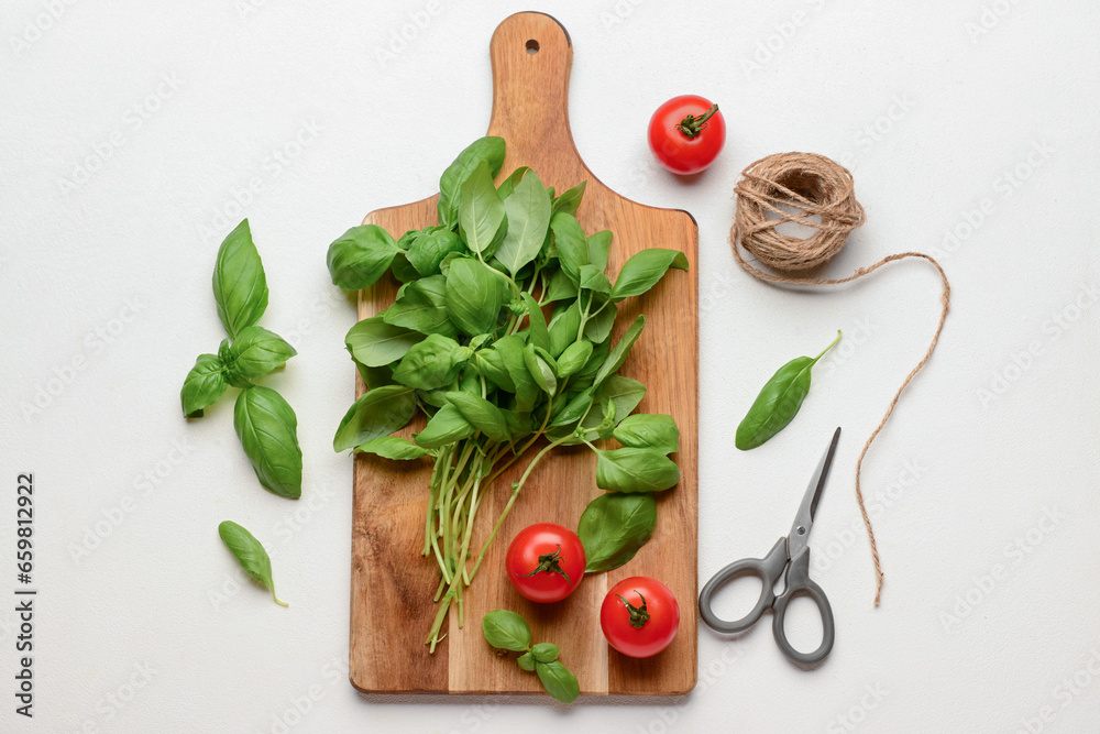 Wooden board with fresh green basil and tomatoes on white background