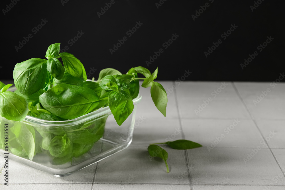 Glass bowl with fresh green basil on white tile table