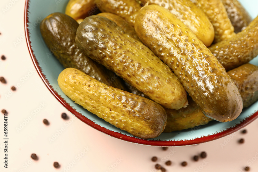 Bowl with tasty pickled cucumbers and peppercorn on white background, closeup